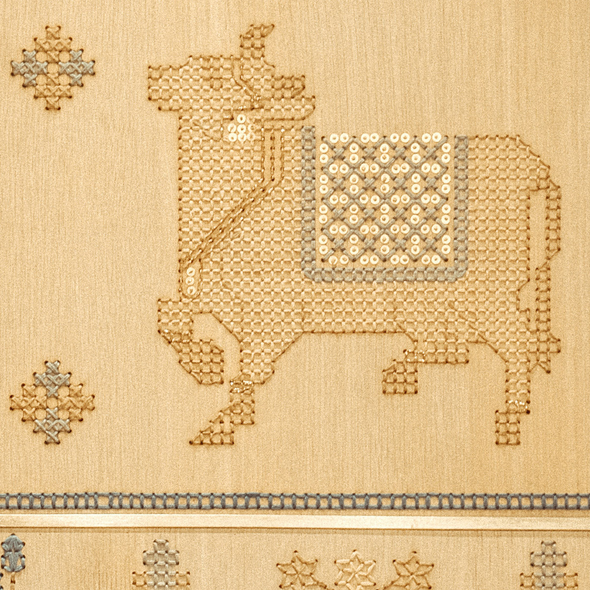Close-up of White Oak veneer embroidered with cotton thread in blue, beige and ochre, featuring carpet-inspired geometric and botanical motifs with subtle gold sequins.
