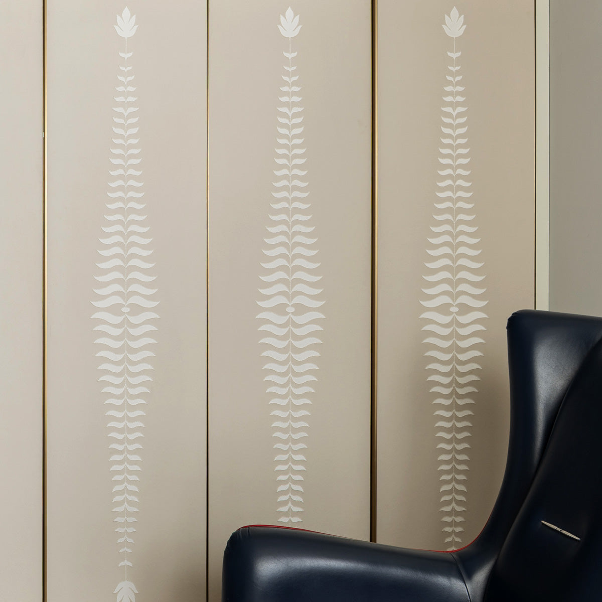 Close-up of hand kantha embroidery outlining fern motif on archival wallpaper.
